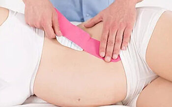 special-treatment-for-pregnant-tummy-close-up-of-physiotherapist-sticking-kinesio-tape-on-pregnant-s